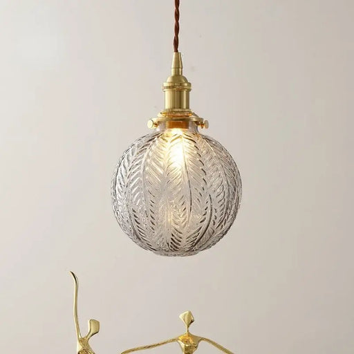 Brass glass lustre pendant light with leaf engravings, featuring a warm glow and Nordic retro-inspired design.