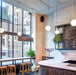 Modern coffee shop interior with pendant lighting, bar stools, and large windows creating a bright and inviting atmosphere.