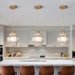 Tiered crystal glass pendant lights illuminating a modern kitchen with a warm, luxurious ambiance over a sleek kitchen island.