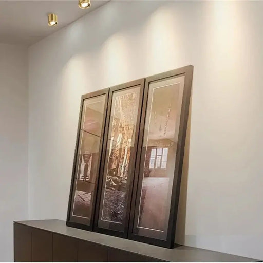 Copper adjustable LED ceiling lights illuminating framed art in a modern interior setting.