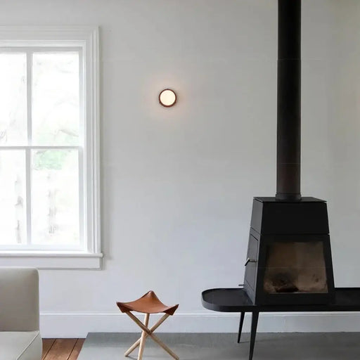 Modern LED wall glass sconce installed in a stylish living room with a cozy fireplace and minimalist decor.