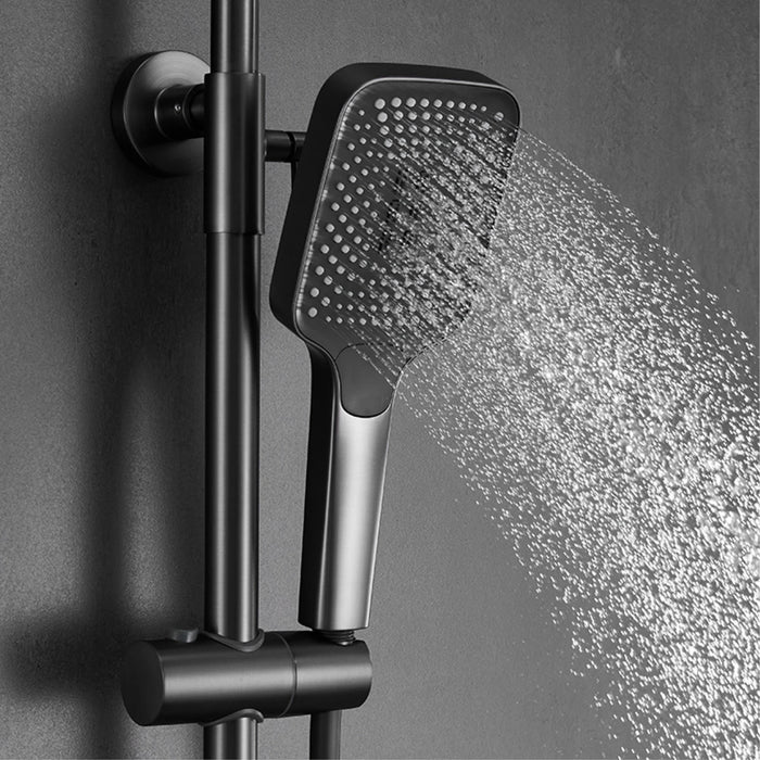 Luxury shower system with digital display and polished brass finish, featuring a square handheld showerhead spraying water.