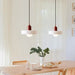 Retro glass pendant lights hanging over dining table with bread and greenery centerpiece in modern, elegant interior.