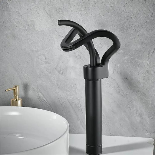 Modern black brass waterfall basin faucet with unique design next to a white sink in a stylish bathroom setting.