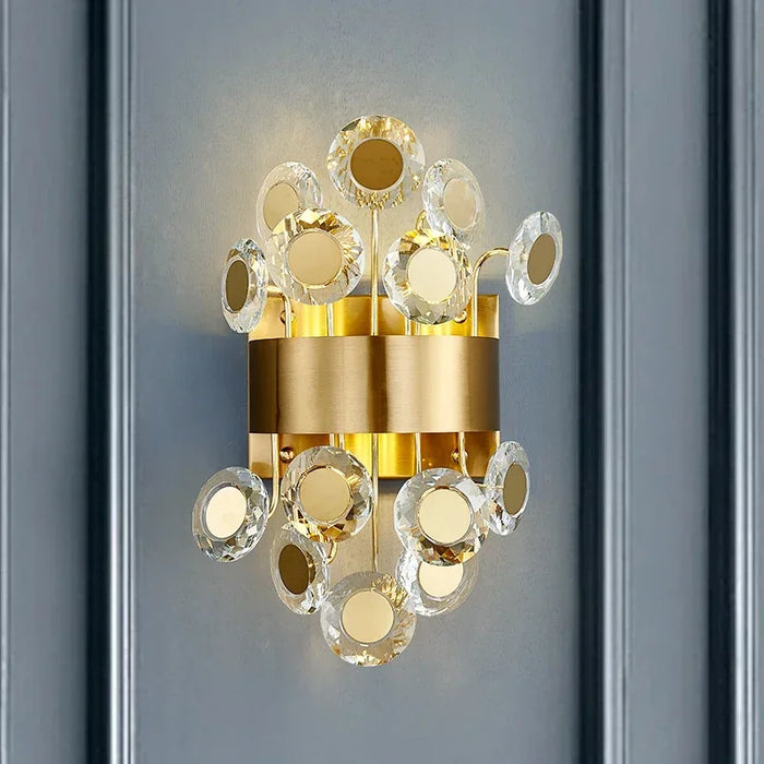 Modern luxury LED crystal wall lamp with decorative gold elements on a grey wall, providing elegant ambient lighting.