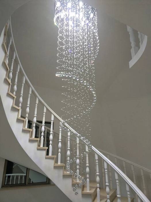 Luxurious K9 crystal chandelier illuminating a grand staircase with sparkling elegance.