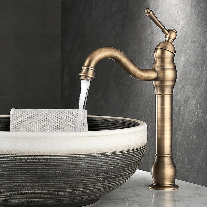 Antique brass long neck basin faucet with water flowing into a ceramic bowl sink, featuring a brushed finish and classic design.