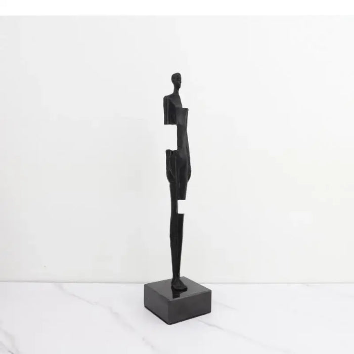 Modern black cast iron sculpture with abstract design on tabletop, minimalist art piece for contemporary decor.