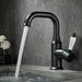 Black deck-mount basin faucet with running water in a modern bathroom setting.