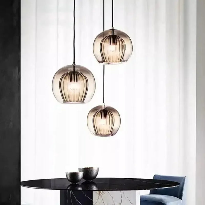 Modern glass double shade pendant lights above a dining table in a contemporary interior setting.