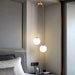 Modern round glass pendant light in a bedroom setting with elegant alloy finish and LED bulbs.