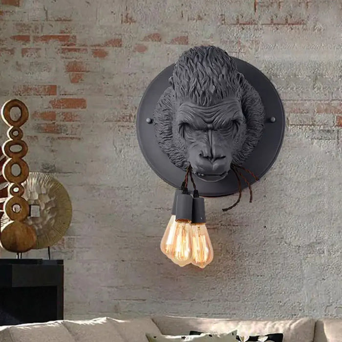 Creative Gorilla LED Wall Lamp in black resin, retro-style home lighting fixture on a brick wall with vintage bulbs.