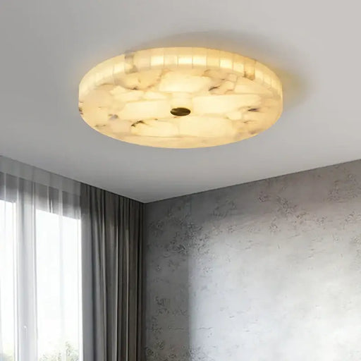 Round alabaster LED ceiling lamp with copper and marble finish in a modern interior setting, providing soft ambient lighting.