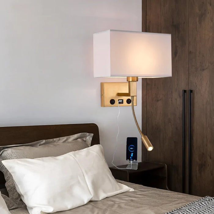 Modern bedside wall lamp with USB port and spotlight, mounted above a bed, enhancing bedroom lighting and convenience.