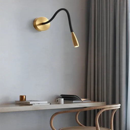 Nordic bronze wall lamp with flexible arm above modern desk in stylish interior.