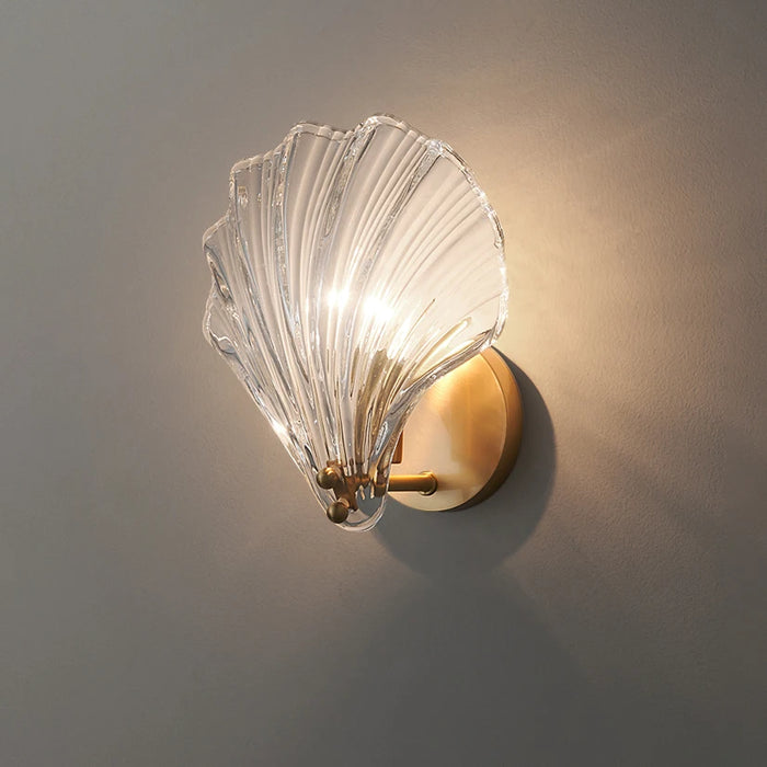 Modern luxury brass wall lamp with clear glass shell design, elegant lighting fixture for contemporary interiors.