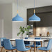 Blue Nordic teardrop wood pendant lights over modern dining table with blue chairs in Scandinavian-inspired kitchen.