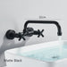 Matte black wall-mount mixer tap with dual handles and a 360-degree rotating spout over a sink filling with water.