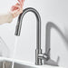 Person using touch sensor on modern kitchen faucet for hands-free operation.