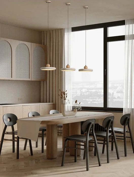 Elegant dining room with modern pendant lights over a wooden table and black chairs in a minimalist design.