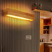 Elegant wood LED wall lamp with adjustable light direction, mounted on a modern wall, showcasing warm illumination and style.