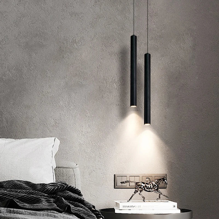 Modern double-head LED pendant light in black aluminum, illuminating a cozy bedroom with minimalist design.