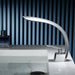 Brushed curved waterfall basin faucet with sleek design on marble countertop in modern bathroom setting