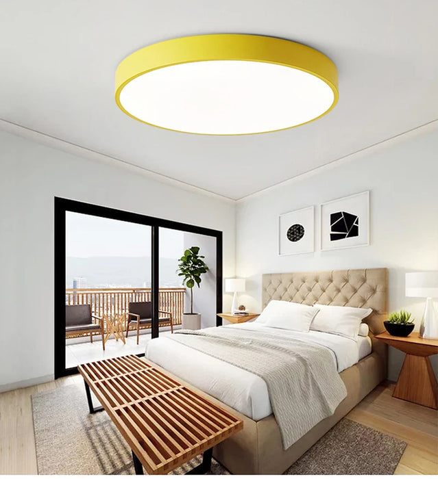 Modern round wooden LED ceiling light with yellow trim in stylish bedroom interior.