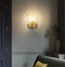 Modern luxury brass shell wall lamp with clear glass shade illuminating elegant home interior.