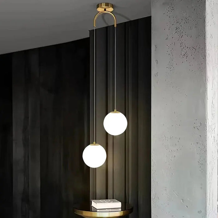 Modern round glass pendant light with dual LED bulbs, elegant brass finish, ideal for bedrooms and living rooms.