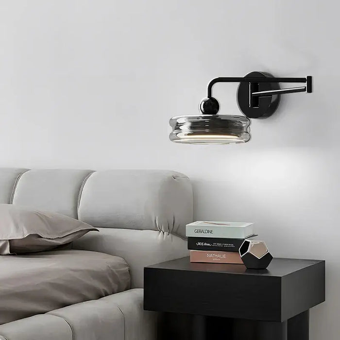 Italian minimalist swing arm wall lamp in modern bedroom setting above bedside table with books.