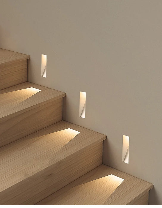 Frameless recessed LED wall lamp illuminating wooden staircase steps with soft light, ideal for foyers and corridors.