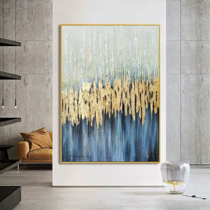 Modern abstract oil painting in blue and gold tones on a vertical canvas, displayed in a contemporary living room setting.