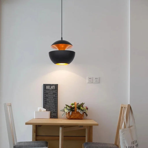 Elegant apple pendant light illuminating a modern dining area with wooden table and chairs.