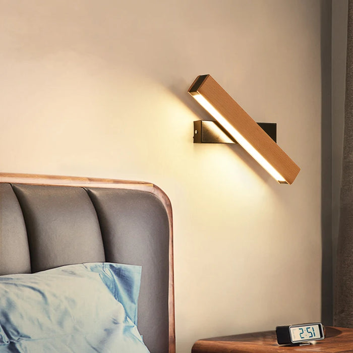 360° Rotatable LED Wall Lamp illuminating a modern bedroom with wooden headboard and digital clock on a nightstand.