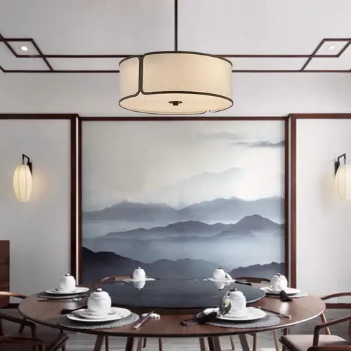 Zen Circular Fabric Chandelier illuminating a dining area with modern decor and a serene mountain painting on the wall.