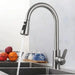 Stainless steel pull-out kitchen faucet with brushed finish and single lever control, showcasing water flow in modern kitchen setting.