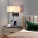 Modern bedside wall lamp with USB and spotlight, mounted above a nightstand in a stylish bedroom setting.