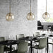 Modern industrial glass pendant lamps in a stylish dining area with minimalist decor and soft ambient lighting.