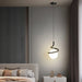 Modern Norse LED pendant lamp with glass and iron design, illuminating a stylish bedroom with switchable light colors, hanging above a side table.