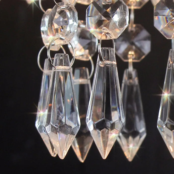 Close-up of crystal pendants on a three-tier chandelier, highlighting elegant design and reflective qualities.