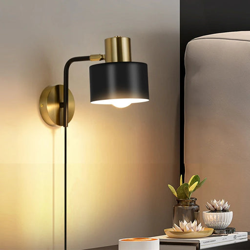 Modern sleek LED wall light in bedroom setting, black and gold finish, illuminating up and down, stylish and functional decor.