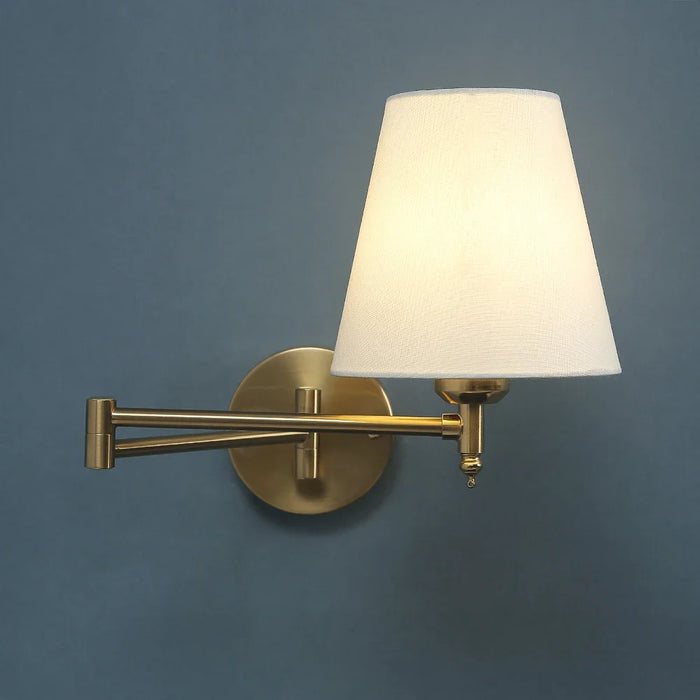 Folding swing arm wall lamp with LED fabric shade, gold finish, providing elegant and functional lighting for home interiors.