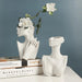 Nordic ceramic body art vase depicting female form, elegantly displayed with flowers on books in a modern home setting.