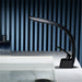 Sleek black curved waterfall basin faucet with modern design next to a bathroom sink.