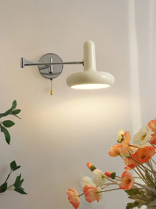 Retractable bedside wall lamp illuminating room with floral decor