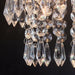 Close-up view of a three-tier crystal chandelier, showcasing intricate crystal design with sparkling details and elegant lighting.