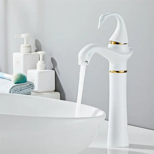 White tall swan basin faucet with gold accents in modern bathroom setting, flowing water into a sleek basin.