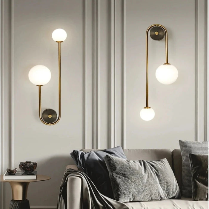 Modern golden LED wall sconces with frosted glass balls illuminate a stylish living room, adding luxury and contemporary elegance.