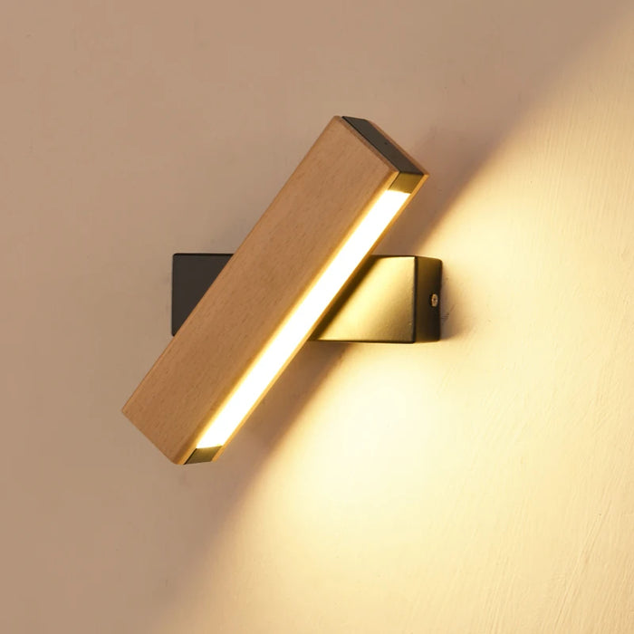 Modern 360° rotatable LED wall lamp in natural wood finish, illuminating a wall with sleek design, perfect for versatile interior lighting.